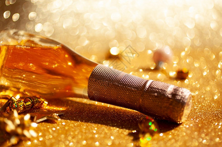 快乐的圣诞或新年配有一瓶玫瑰香槟和金色闪亮背景的花彩装饰喜庆布基和影子的侧观以及庆祝党的创造概念以庆祝圣诞节或新年瓶子葡萄酒背景图片