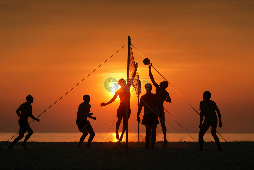 青少年海边玩沙滩排球日落剪影图片