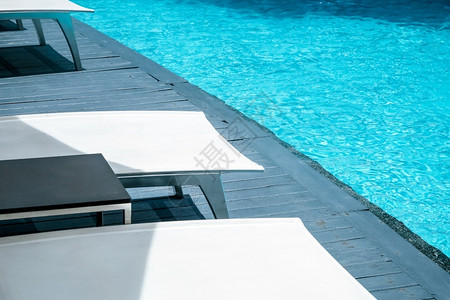 酒店泳池旁边的白色躺椅家具高清图片素材