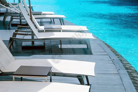 酒店泳池旁边的白色躺椅巴蜀高清图片素材