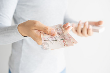 亚裔妇女用手在白背景上数钱她手里拿着泰兰的货币铢金融富有银行预算高清图片素材
