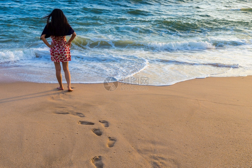 假期年轻女子独自在空的海滩上行走阳光从天空落下场景松弛图片
