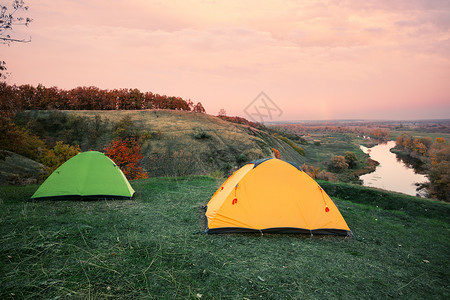 河岸的橙色和绿帐篷露营图片