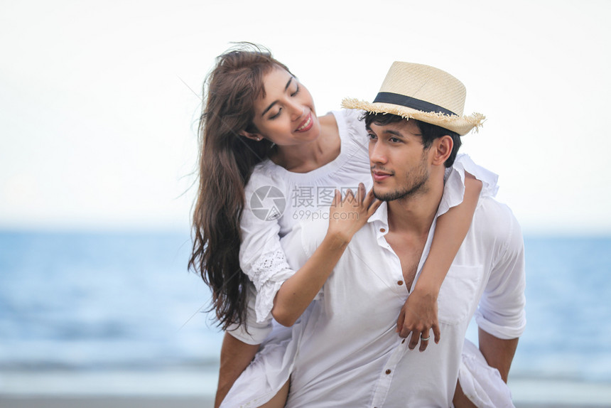 放松户外成年人快乐的浪漫情侣人手牵在海滩上散步图片