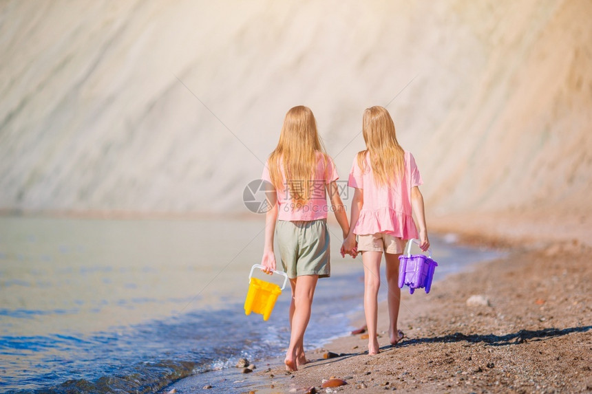 可爱的小女孩在海滩上散步玩得开心的可爱小女孩在海滩上水热带夏天图片