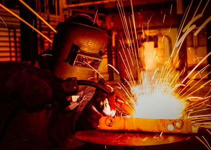 工业的蓝色劳动者工业人戴保护面罩在汽车厂焊接金属图片