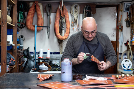 工厂手艺品纺织在他的小型车间里做皮革的工匠图片