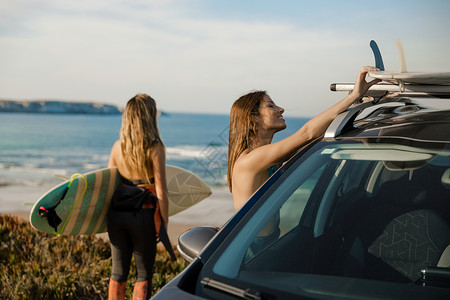 两个美丽的冲浪女郎与她的车在海岸线附近并准备冲浪荒野为了夏天图片