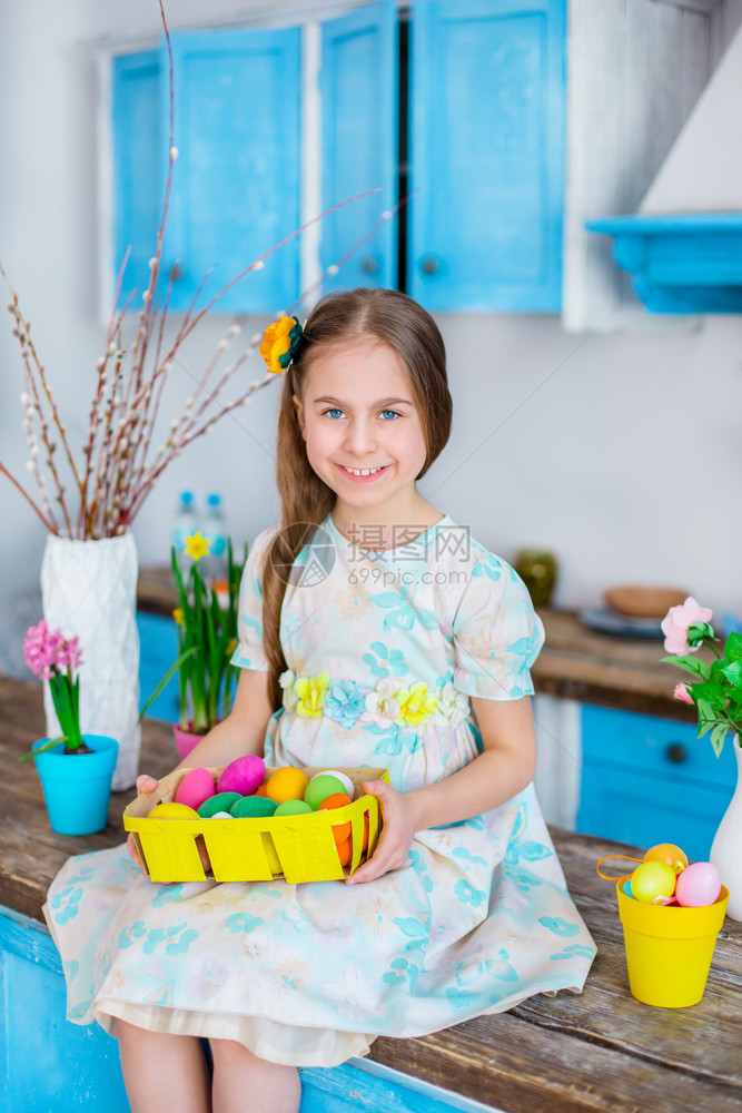 快乐的装饰可爱女孩拿着篮子和彩蛋在厨房煮饭为假日复活节可爱女孩做饭带彩蛋的篮子象征图片