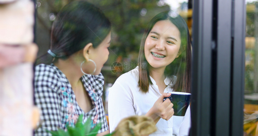 女人们两个亚裔妇女喝咖啡和两个开心愉快的女人在咖啡馆闲聊漂亮的图片