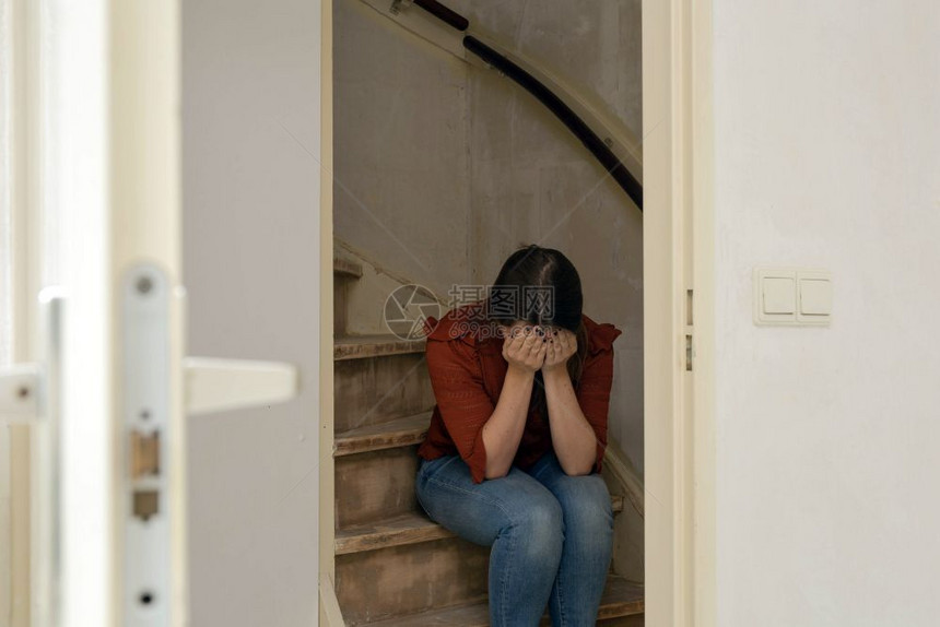 焦虑悲伤的女人独自坐在楼梯上哭泣房子仍然需要翻新建设和的概念特写悲伤的女人独自坐在楼梯上哭泣房子仍然需要翻新建设和的概念坐着装修图片