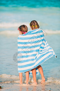海滩边游泳后裹着毛巾的可爱小女孩背景图片