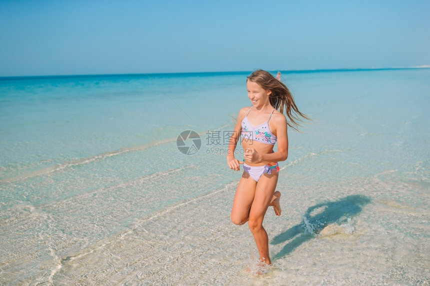 小女孩玩得开心在热带海滩的浪中漂浮在度假时海滩上可爱的小姑娘情感乐趣图片