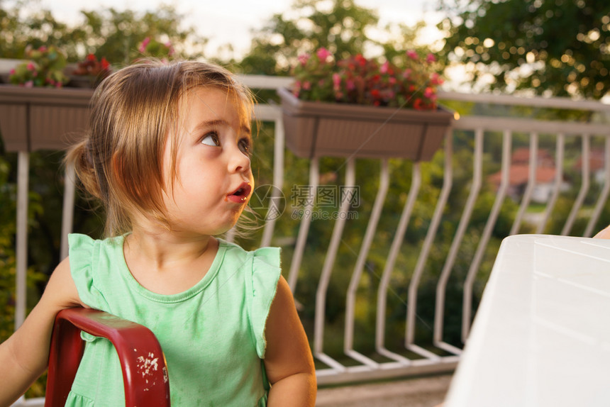 夏日在桌边吃西瓜的金发小女孩图片