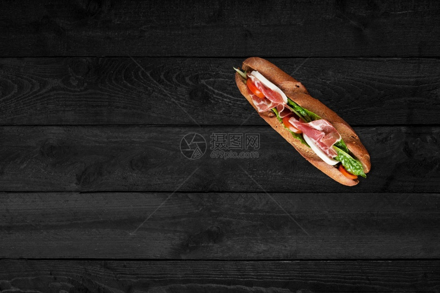 黑色木桌上的三明治图片