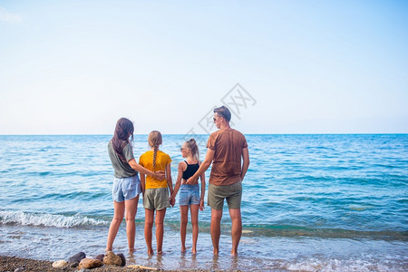 一种父亲微笑四口家庭一起在海滩上玩乐度假的年轻家庭有很多好玩的地方图片