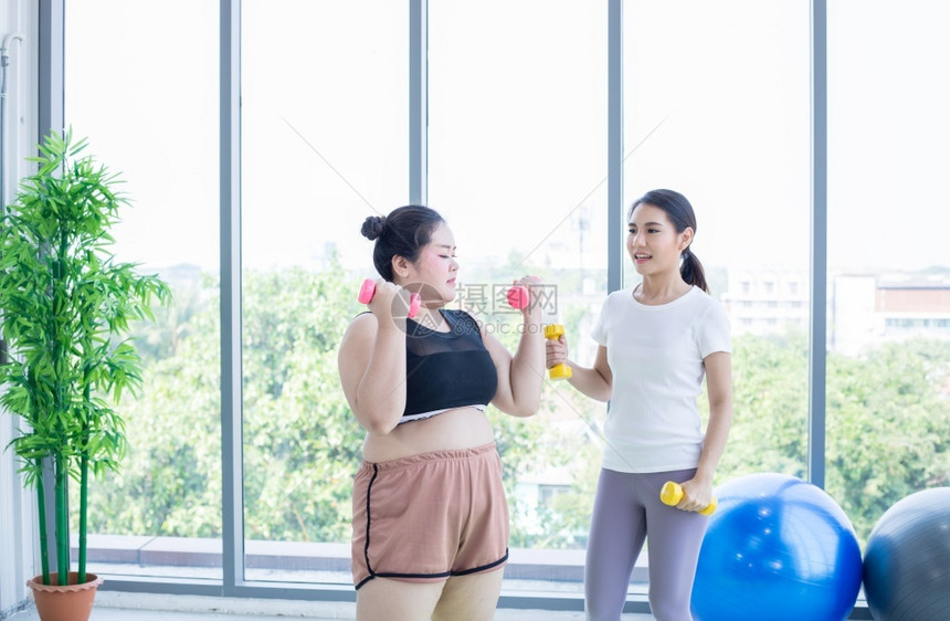 女孩胖的闲暇两个亚裔妇女在家里用哑巴操练图片