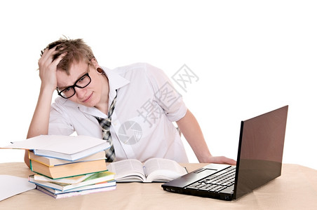 学习电脑沉思的沮丧学生坐在白种背景孤立的书桌后坐落在一个桌子后面图片