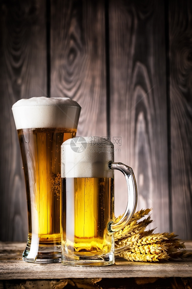 一种小麦玻璃杯和一轻啤酒有泡沫和耳朵在木制背景上玻璃杯和一轻啤酒有泡沫和耳朵图片