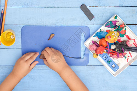 手臂学龄前儿童面团孩子们的双手雕刻在一张蓝色表格上的粘土图从到下训练高清图片素材