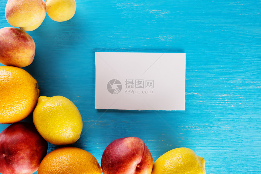 油桃子蓝色背景上的新鲜热带水果附有笔记纸从上方查看食物背景健康天然食品的概念蓝色背景上的新鲜热带水果附有笔记纸柑橘图片