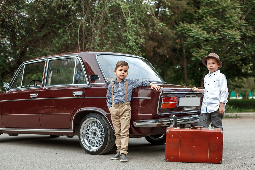 冒险老的汽车两个穿古老衣服的白人小男孩站在一辆旧车旁边图片