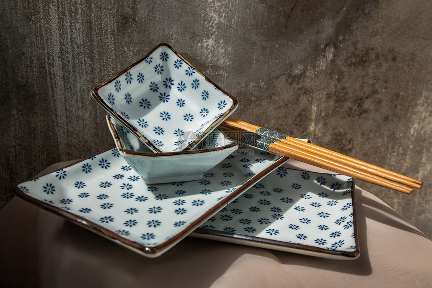 墙粉色的水泥桌布上的一套陶瓷板碗和木棍陶瓷餐具美丽的安排复制空间选择焦点等图片