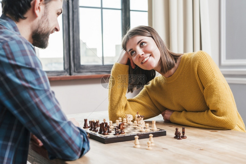 笑地面美丽的一起玩国际象棋家的年轻夫妇图片
