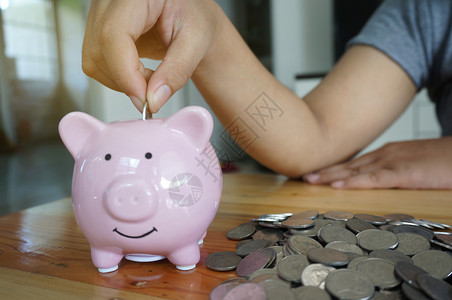 成本钱薪水妇女用手在小猪银行上打硬币图片