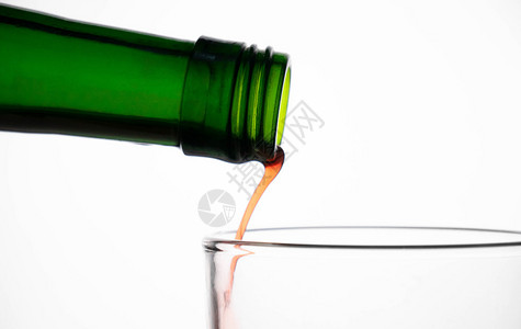 喝水果运动从绿色瓶子倒到玻璃杯的果汁紧贴地从绿瓶子倒到白色背景上图片