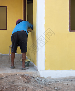 建造内部的装修当地画家在乡间房子的新墙壁上画黄色的作背景图片