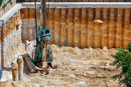 旋挖钻户外污垢大型挖掘机安装钻混凝土柱加固未来高层建筑地基空视角复制间重型挖掘机配合钻加固未来高层地基建造坑背景