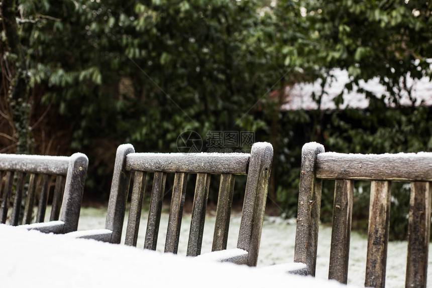 树木头降雪在后院花园的寒雪中被覆在里冬季Wooden温室花园的椅子被雪盖在后院花园的雪里图片