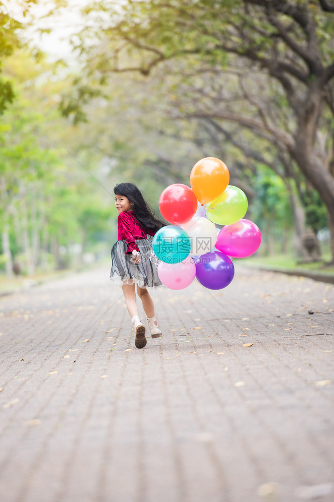 幸福孩子们假期快乐的女孩们在公园度假节日微笑带着多彩的气球跑来去图片
