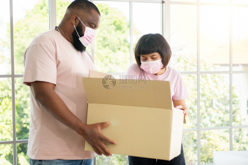 人们一个外科面具携带纸板盒装在新房子的移动日屋内搬家概念租房住家搬和屋主非洲人快乐的图片