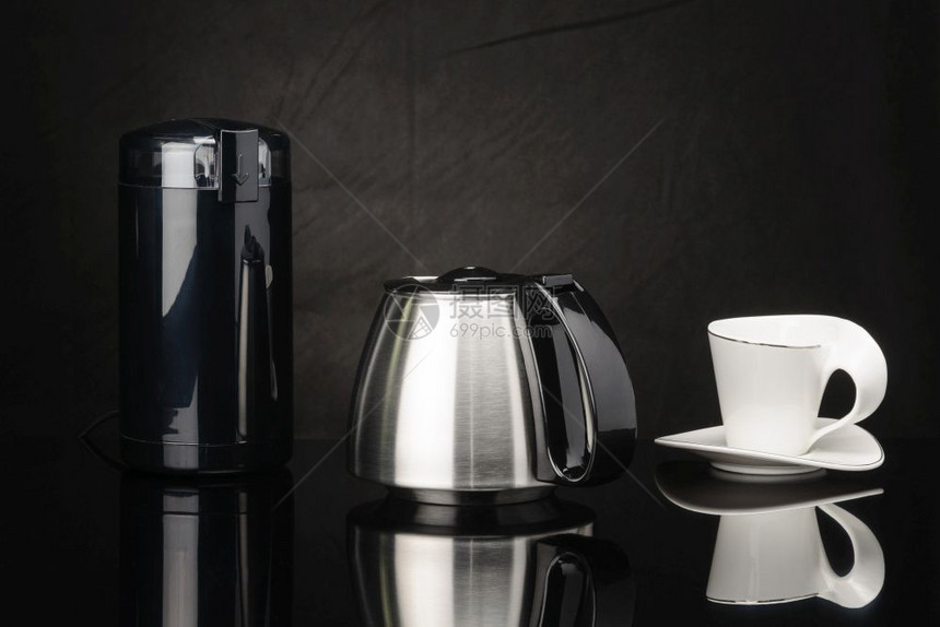 喝机器阿拉比卡黑镜背景咖啡杯附近的不锈钢咖啡壶和研磨机黑镜背景咖啡研磨机和杯壶图片