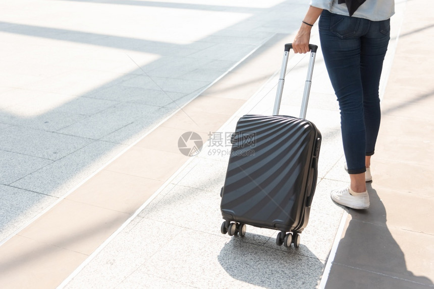 包旅行和商务主题妇女穿着牛仔裤独自一人巡游和环世界各地旅行的独身女孩在机场上近身妇女和手提箱式牵推车行李背部航班图片