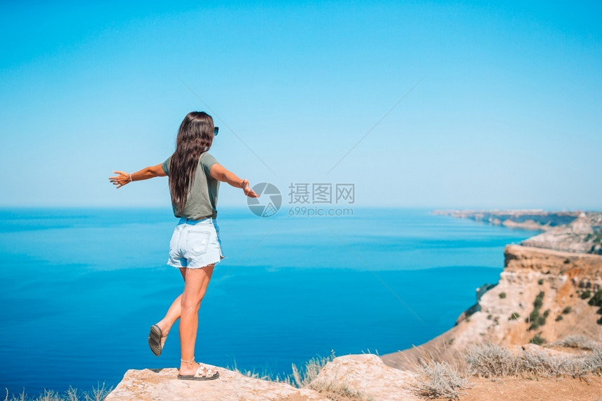 自然闲暇在悬崖边缘度假的快乐女人露天旅游客在悬崖海岸边缘喜悦图片