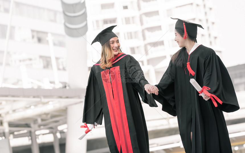 两位身穿红色学士服拍照的微笑女孩图片