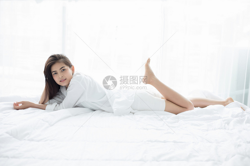 枕头美丽的年轻微笑亚裔女士坐在床上醒来后床上躺休息后早在卧室里拉伸展唤醒寝具图片