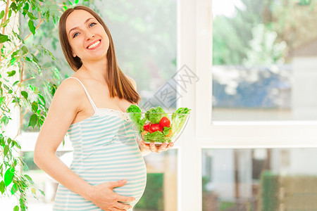 产假饮食前笑着的孕妇吃沙拉照片叉高清图片素材
