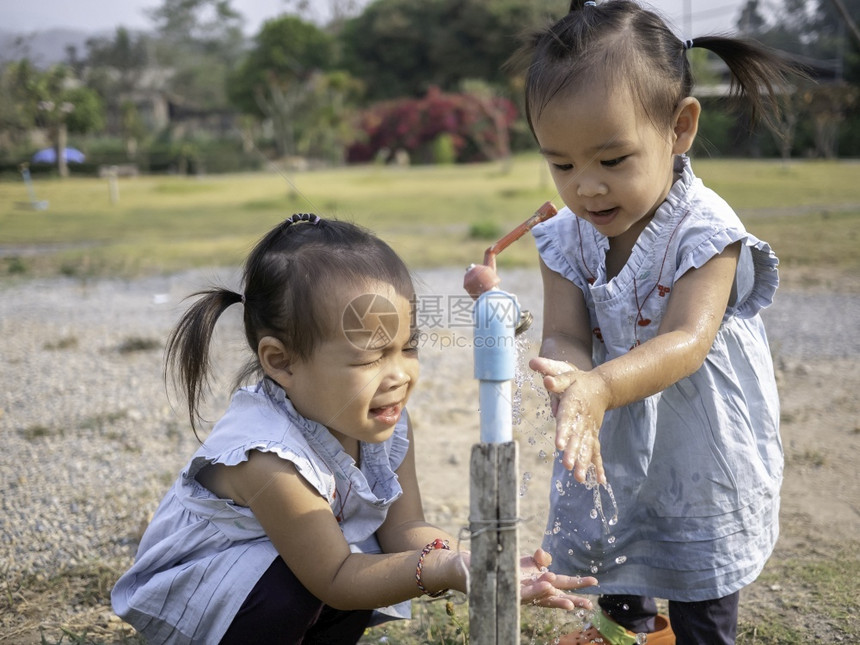 湿的亚洲小女孩和妹用花园的钢水龙头洗手从花园里肖像关心图片