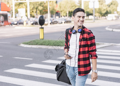 镇外部快乐的年轻人与手机横越街男图片