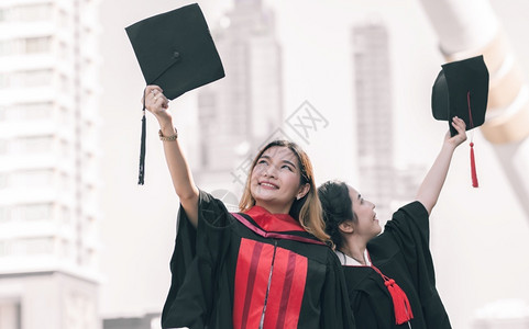 学校两名身着制服帽子和毕业后快乐笑的亚裔女学生教育概念户外年轻的知识高清图片素材