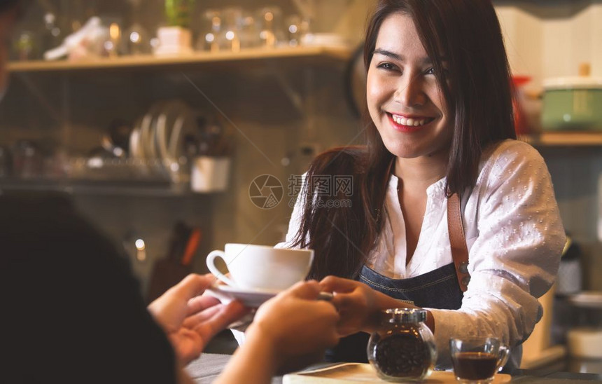 茶食物白种人美丽的亚洲女律师协会向在反酒吧背景的顾客提供热咖啡微笑着的妇女和工作以及图片