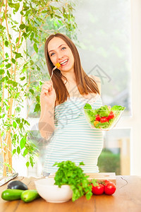 胃莴苣笑着的孕妇吃沙拉照片保持美丽的高清图片素材