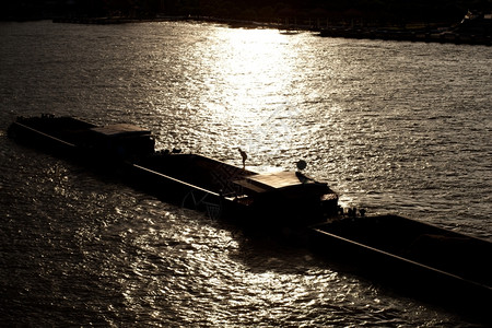 棕色的大部分一般货轮夜间阳光照耀在水面反射河很温暖油图片