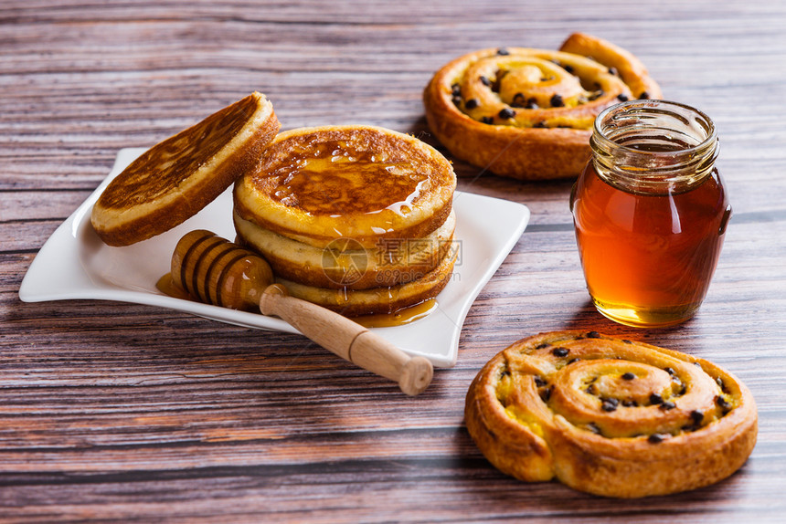 饼子美味的木制背景上含液体蜂蜜的煎饼木头图片