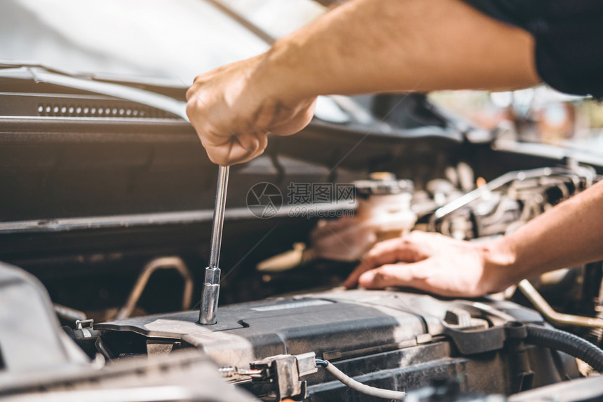分解力量在车库工作的汽修理技术员在汽车修理服务和维汽车检查中工作的汽车修理手电池图片