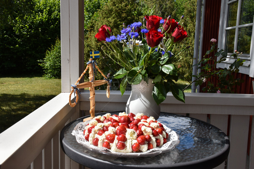 配有瑞典的草莓蛋糕花朵和小红杆夏季装饰品自然蓝色的奶油图片